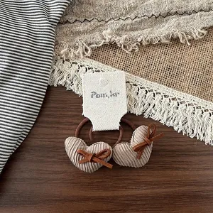 Détail de pinces à cheveux cœur en tissu avec nœuds marrons sur carte