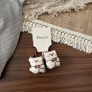 Paire de chouchous ours en peluche avec élastiques marrons sur carte de présentation