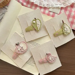Set of four handmade embroidered hair clips featuring apple bird and pear designs on beige card