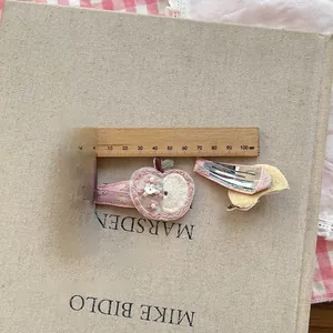 Close-up of pink apple embroidered hair clip set with pearl detail and wooden ruler