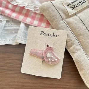 Detail of handmade pink bird hair clip with floral embroidery and mini pearl accents