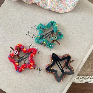 Detail of three crochet star hair clips with colorful dots and buttons on beige fabric