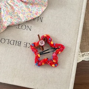 Close-up of red star knitted hair clip with colorful dots and a brown leather bow