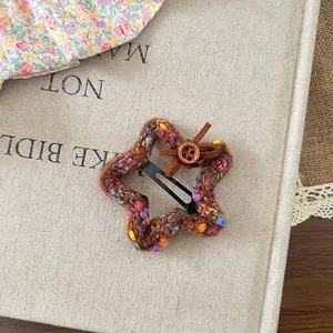Detail of wool knit star hair clip with brown leather bow and small wooden button accent