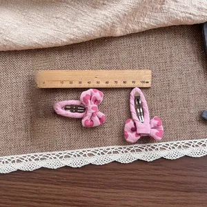 Détail de barrettes à cheveux nœud rose avec motif cœur mesurant 6cm sur tissu rustique