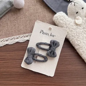 Détail de barrettes à nœud en tissu gris à pois pour filles sur une carte décorative