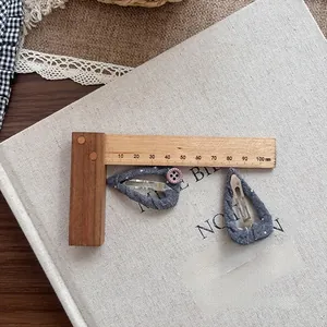 Detailed view of 50mm grey polka dot fabric hair clips with small pink button accent