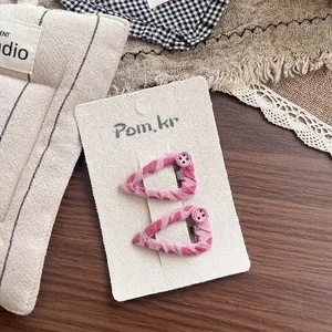 Detail of pink fabric-wrapped BB clips with small buttons on a display card