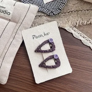 Detail of two purple handmade fabric hair clips with star patterns and resin button accents