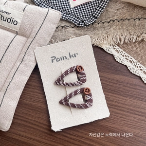 Detail of brown plaid fabric hair clips with button accents on display card