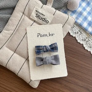 Détail de barrettes à nœuds en tissu à carreaux bleus et gris sur carte d'affichage