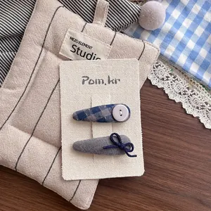 Détail de pinces à cheveux à carreaux bleus avec boutons blancs et nœuds en tissu