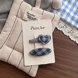 Détail de barrettes à cheveux en tissu écossais bleu et gris de formes cœur et ovale