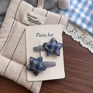Détail de barrettes en tissu à carreaux bleu et gris en forme d'étoile avec couture