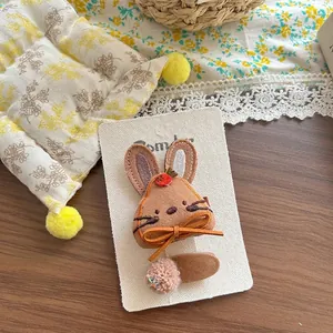 Détail de la pince à cheveux lapin en tissu brodé avec mini carotte et pompon assorti