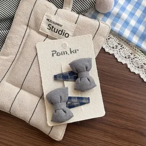 Détail de barrettes à cheveux en tissu à carreaux bleus et nœud gris sur carte