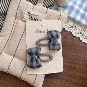 Détail de barrettes à nœuds en tissu à carreaux bleu et gris sur carte blanche