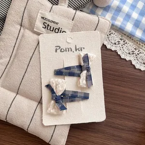 Détail de barrettes à nœuds en tissu à carreaux et dentelle sur un support