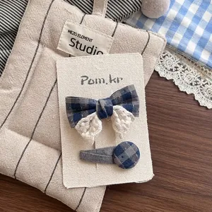Détail de la barrette à nœud écossais bleu avec dentelle sur tissu matelassé