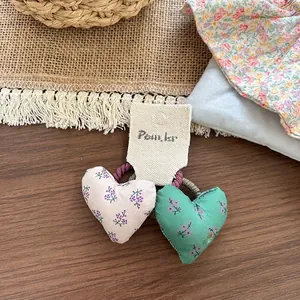 Detalle de coleteros de tela floral en forma de corazón en tarjeta de presentación