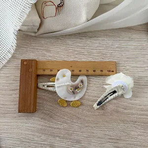Détail de la pince à cheveux canard brodé et fleur en dentelle avec guide de taille