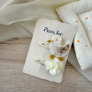 Détail d'une pince à cheveux oiseau brodée et fleur en mousseline 3D sur carte