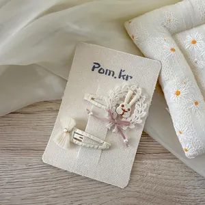 Détail de barrettes brodées lapin et dentelle sur un support de carte élégant