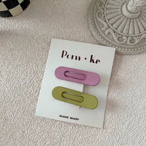 Detail of matte pastel drop hair clips in pink and green on a branded display card