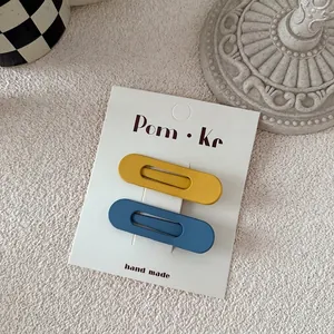 Close-up of matte waterdrop BB hair clips in blue and yellow on brand display card