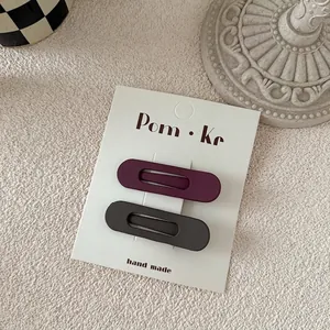 Macro detail of matte teardrop BB hair clips set in dark purple and deep gray tones