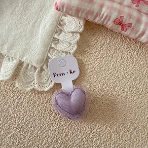 Gros plan d'un chouchou cœur en maille violette présenté sur une carte blanche
