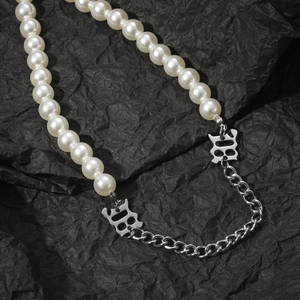Collana hip hop con perle e catena d'argento con ciondoli logo B su sfondo nero rugoso