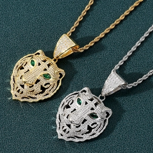 Détails de pendentifs tête de tigre en or et argent avec gemmes vertes sur fond sombre