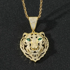 Gros plan du pendentif tête de tigre doré avec zircone et yeux en pierre verte