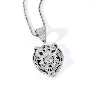 Détail macro du pendentif tête de tigre avec yeux en zircon vert et chaîne torsadée