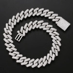 Close-up of a silver-colored iced-out Cuban link chain with a square clasp on black background