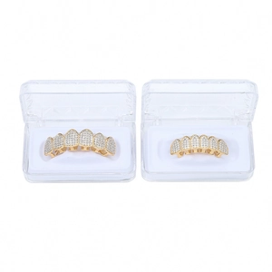 Λεπτομέρεια από χρυσά grillz hip hop με ζιργκόν pavé σε διαφανείς θήκες προβολής