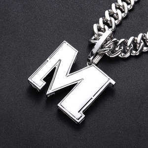 Vue macro d'un pendentif M argenté avec émail blanc sur une chaîne cubaine assortie