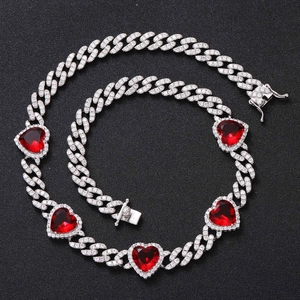 Macro shot of silver hip hop Cuban link chain with sparkling red heart-shaped stones