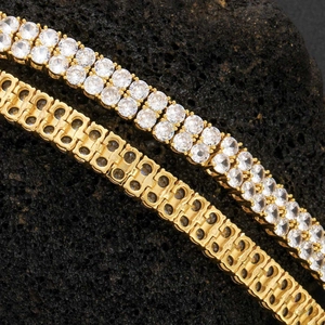 Vue macro d'un bracelet tennis doré à double rangée de zircons sur pierre volcanique