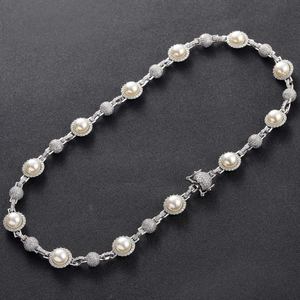 Macro shot of hip hop pearl necklace with diamond-encrusted rings and pavé metal spheres