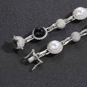 Dettaglio macro della collana d'argento con perle bianche e nere e maglie in zircone