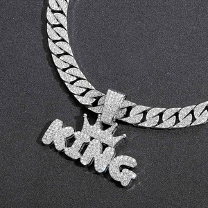 Macro shot of silver-colored iced out KING crown pendant on a sparkling Cuban link chain