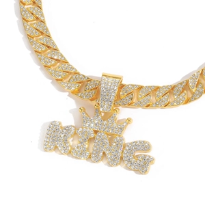 Close-up of gold iced-out KING crown pendant with shimmering crystals on Cuban link chain
