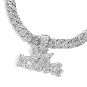 Macro shot of silver hip-hop KING pendant with crown and iced-out zircon stones