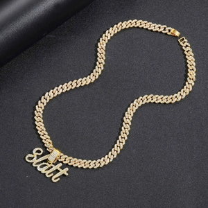 Vue macro du pendentif Slatt doré et de la chaîne cubaine sertie sur fond noir