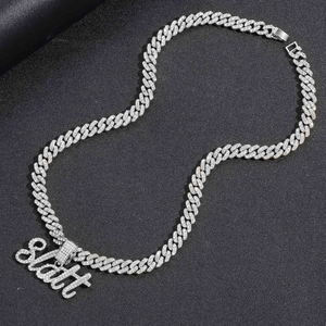 Détail de la chaîne cubaine hip hop avec pendentif SLATT glacé sur un fond noir texturé