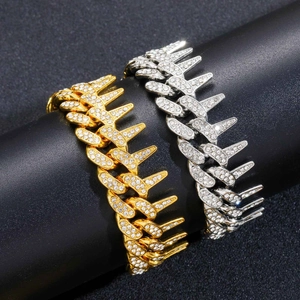 Détail macro de chaînes cubaines à pointes or et argent avec cristaux sur support noir