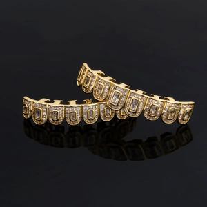 Iced out hip hop grillz set with baguette zircons in gold plating on black reflective surface