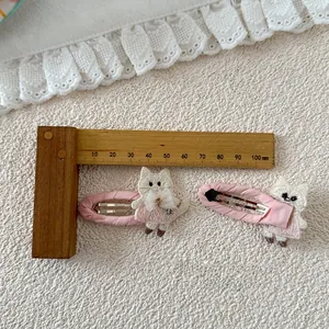 Detalle de pinzas de encaje rosa con gatito bordado y adornos de perlas para el cabello